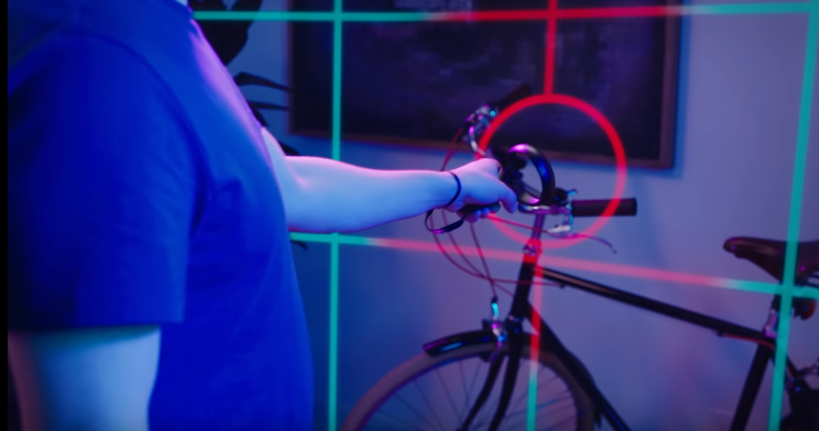 Hand holding controller pointed at a bicycle and grid is now red where his hand is
