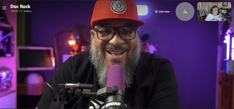 #title# Doc Rock smiling, purple room purple mic red ha