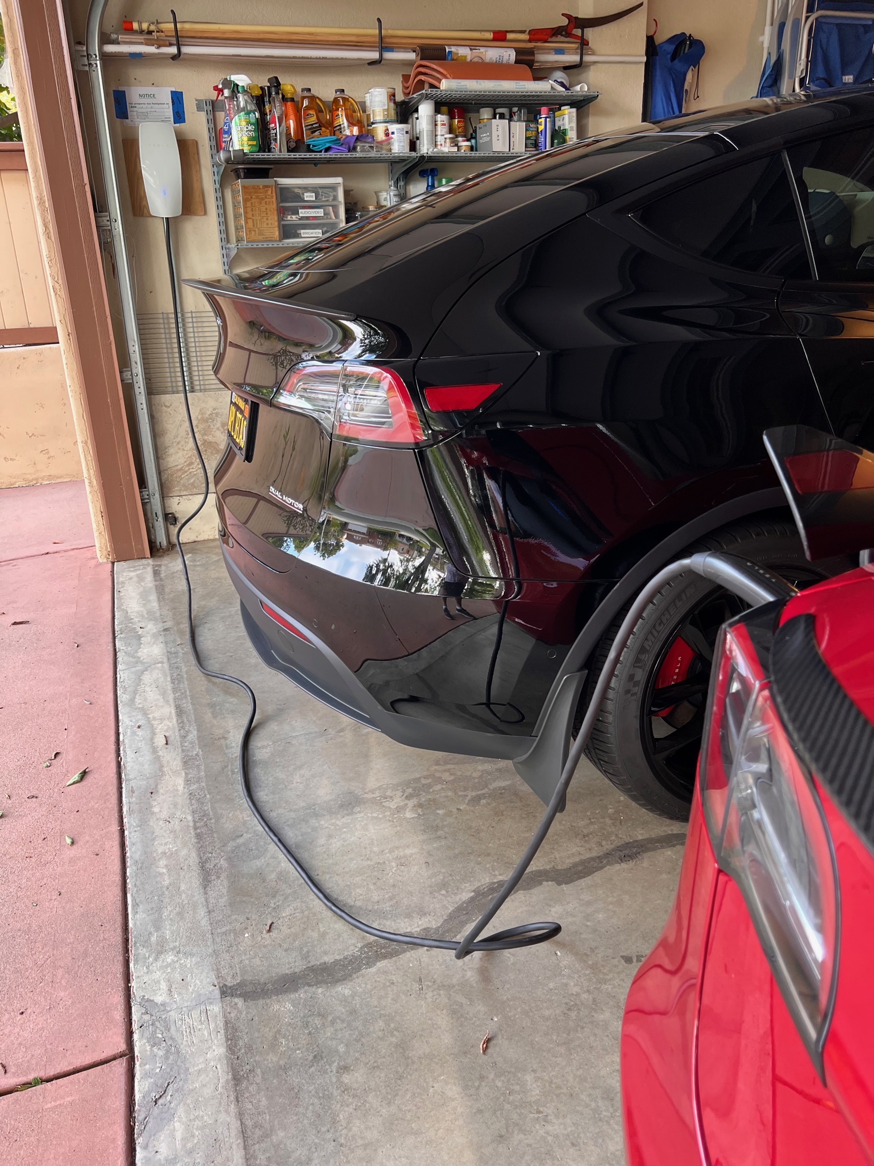 Charging My Car at Home.jpeg Tesla walll charger next to Steve's Black Model Y with Cable Dragged Over to My Red Model 3