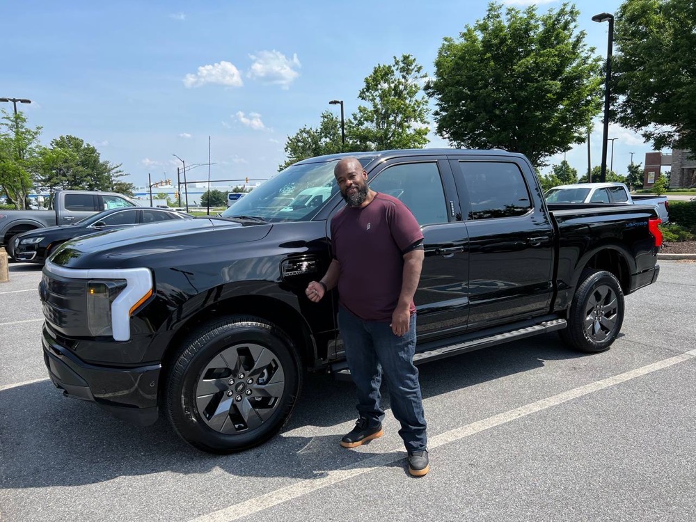 Chris standing in front of his Ford 150 Lightning truck in black on black