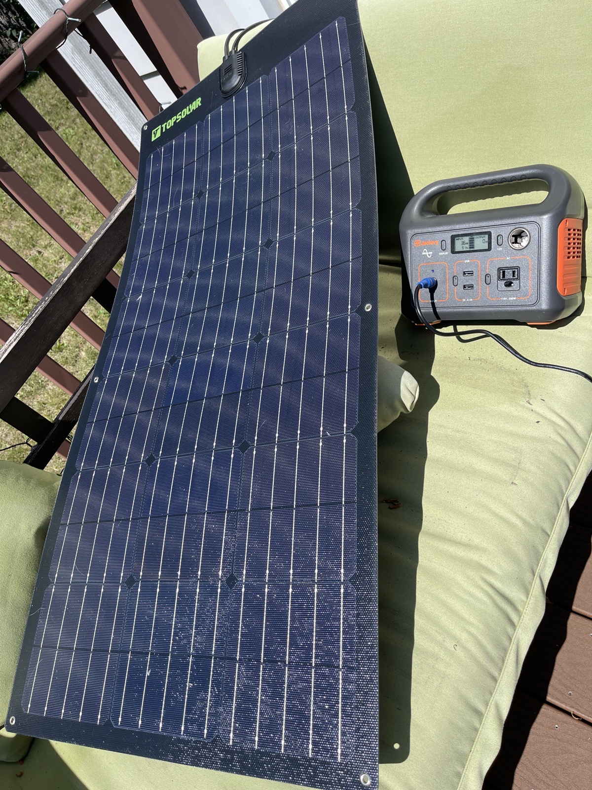 TopSolar panel laid out on a lawn chair charging the Jackery battery