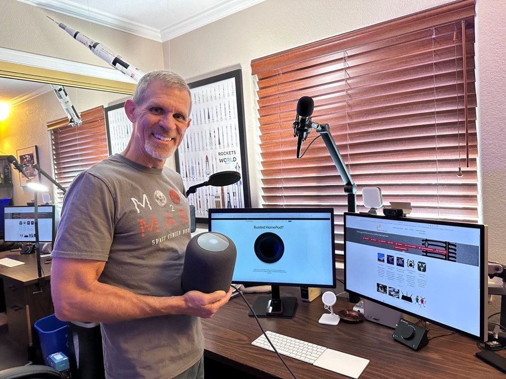 Steve holding his fixed HomePod with Nic and Allisons websites on two screens and a Saturn V rocket hanging in the corner of the room  his favorite rocket