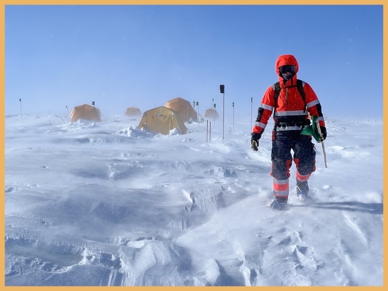 Greenland Person Walking in Full Gear in Snowstorm Next to Tents