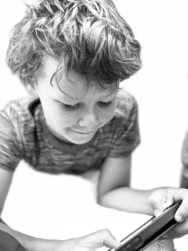 young boy looking down at a phone captured with one of the iPhones special lighting effects in portrait mode