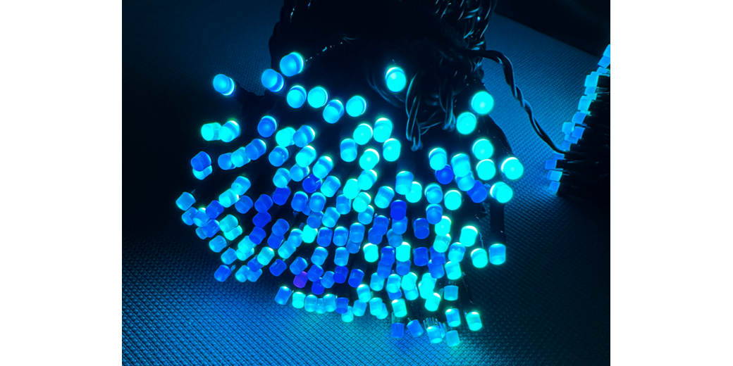 A bundle of blue and green LEDs edge on glowing against a dark table