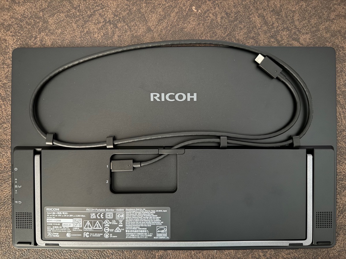 RICOH 150BW flat on a table showing the back with cable management and stand folded up.