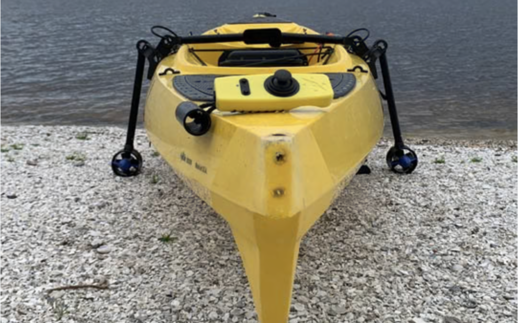 Front view of a kayak with the PacMotor attached around the kayak. An electric motor with a propeller is attached to each of two rods that extend into the water on either side of the kayak.