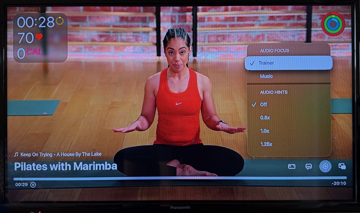 Apple Fitness+ showing a woman sitting cross legged and a popup showing the option to change audio focus.