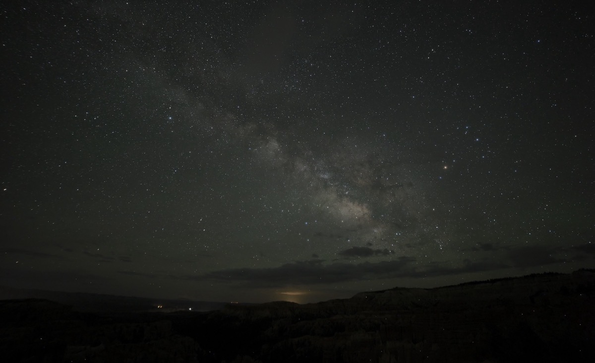 In this picture you can see a portion of the Milky Way galaxy including most of the center.  This picture was taken on the new moon in May 25 on the rim of Bryce Canyon near sunrise point.  In the distance you can see the glow of Page AZ which is nearly 100 miles away as the crow flies.  In the foreground, you can see the hints of the canyon as well as some sensor errors which show up and dots of light below the rim of the canyon.  I also like this picture because of the thin low hanging clouds which brought a unique perspective.