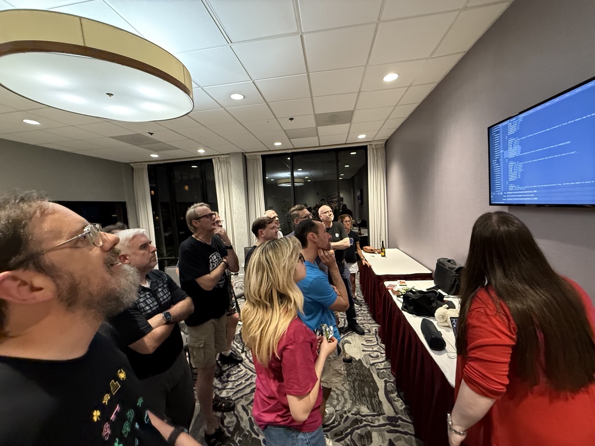 TV screen with JavaScript and a bunch of nerds studying it.