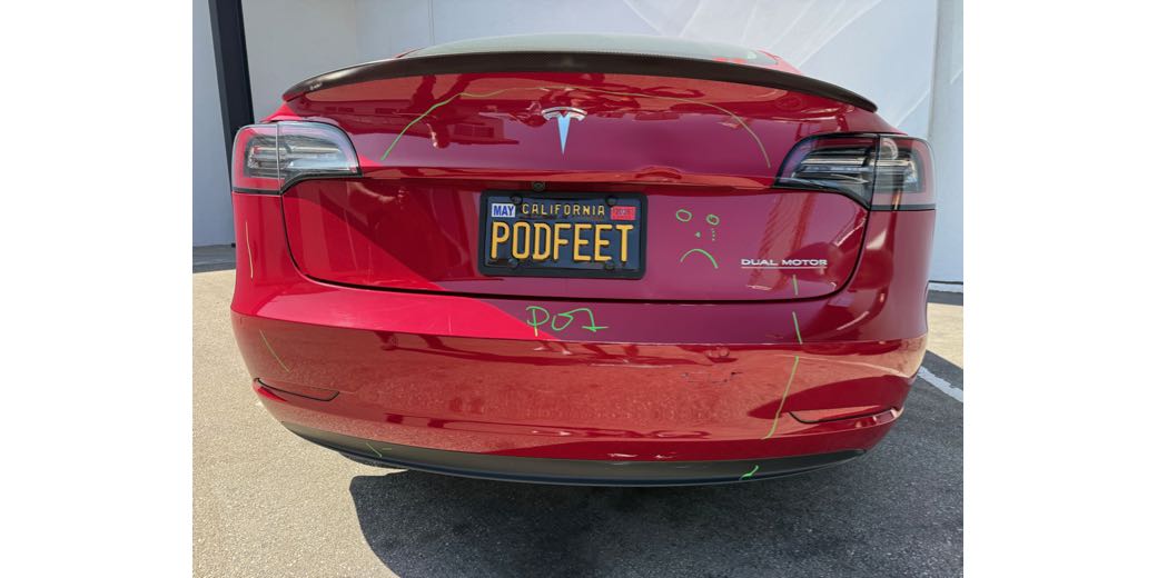 rear end of my car drawn on by the repair people. it is yellow green ink and they encircled the damage areas including writing POI for point of impact. they let me draw on it too so I drew a sad face.