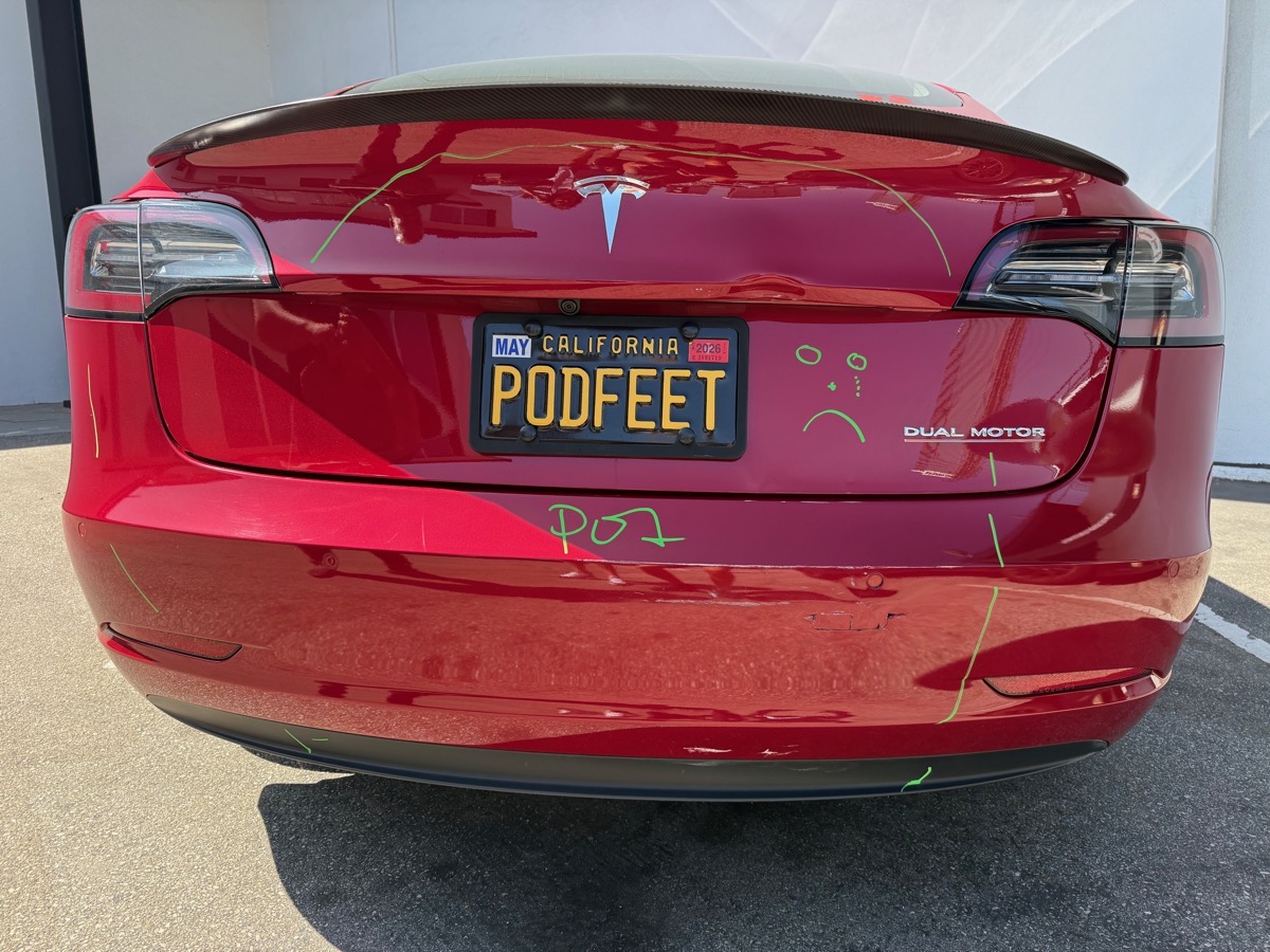 Model 3 drawn on by repair people. there are yellow green lines encrciling what has to be repaired. it says POI for point of impact. i drew the sad face on the back.