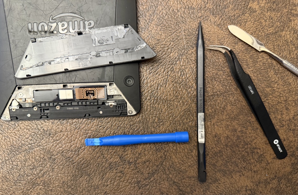 Kindle trapezoid cover off showing adhesive and four tools.