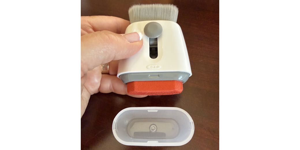 OXO clean and swipe tool as described in the article. It is positioned vertically with the brush extended up and the microfiber cloth end down with the cap off