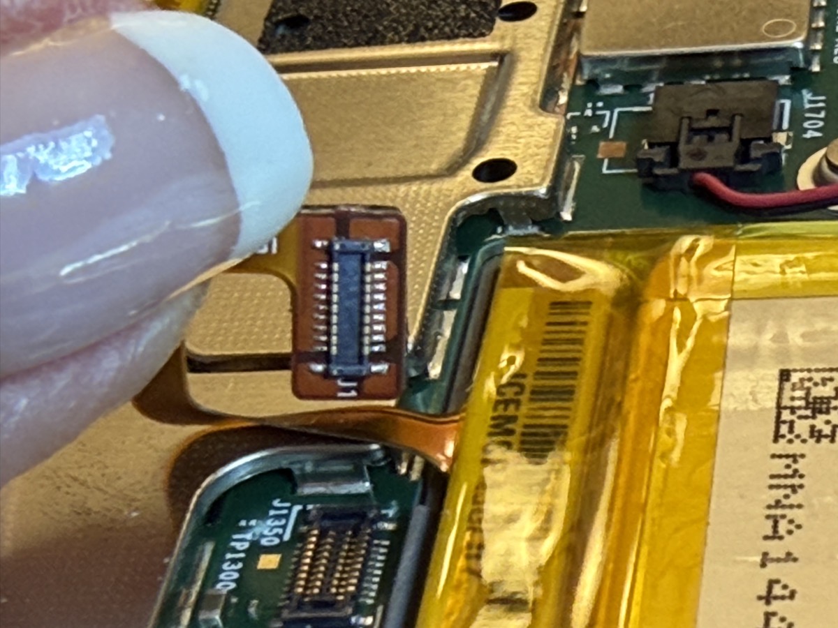 Womans thumb holding up the tiny battery connector demonstrating scale.