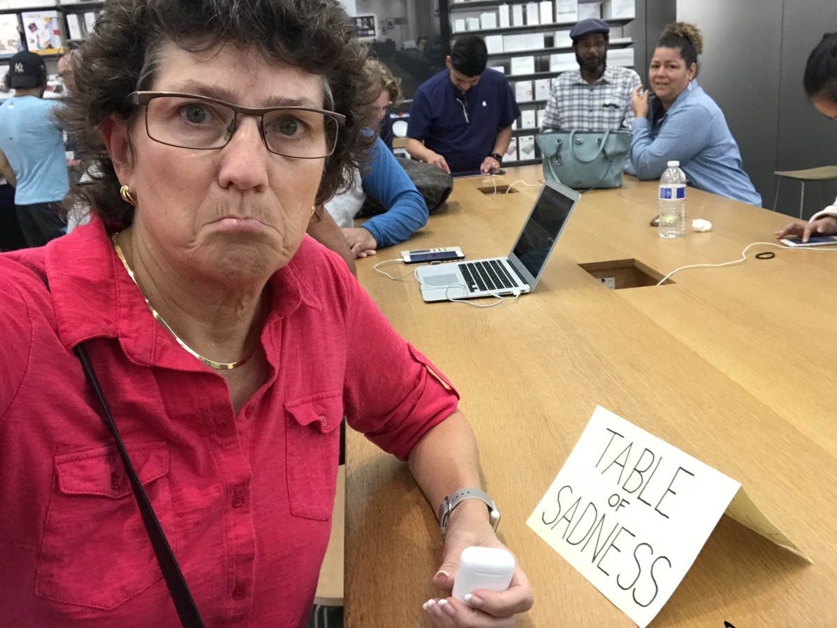 Allison sitting at the genius bar with a sign that says table of sadness.