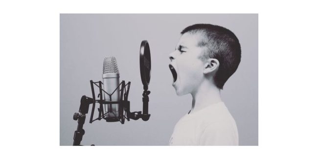 kid yelling into a microphone on a stand with a pop filter and vibration isolator