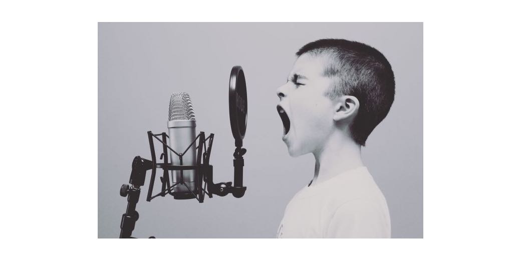 kid yelling into a microphone on a stand with a pop filter and vibration isolator