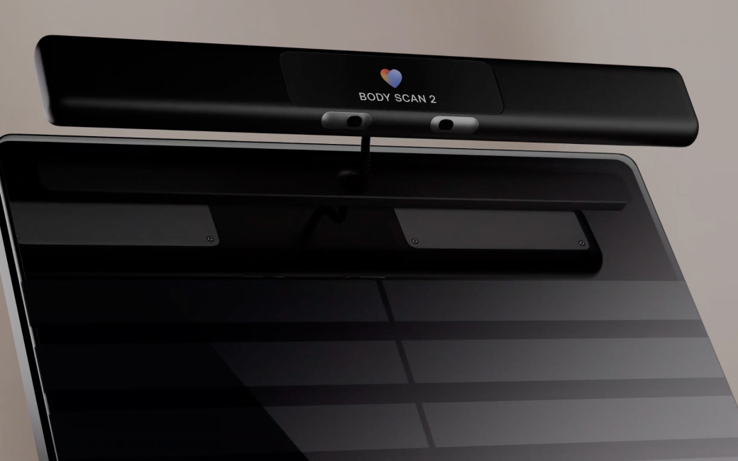 Close-up of a black Withings Body Scan 2 smart scale, showing the glass weighing surface and a raised top bar with sensors and the “Body Scan 2” label.