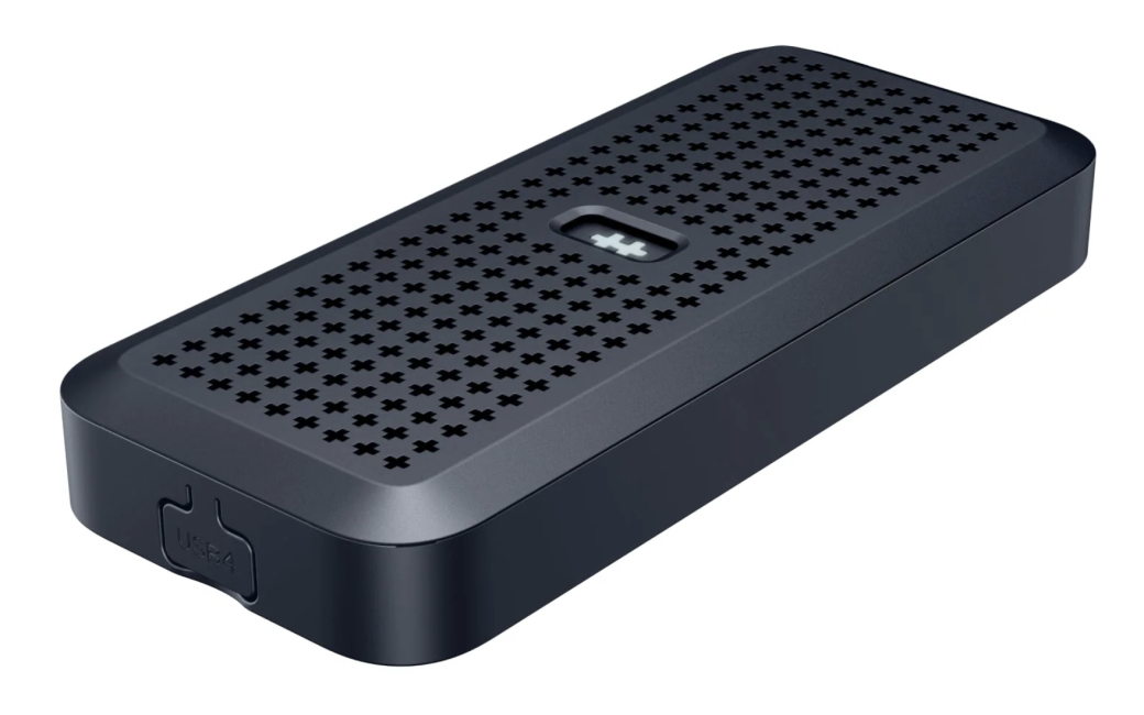 HyperDrive SSD Enclosure is show as a compact, rectangular dark gray electronic device with rounded edges. The top surface has a grid of small plus-shaped ventilation holes and a small recessed indicator window in the center. One end shows a labeled USB-C port. The device is shown on a white background.