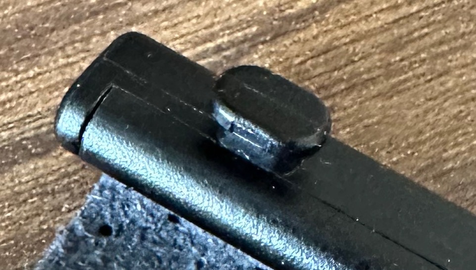 Post-closeup-full.jpeg Closeup part of the Strapsicle folding cover, showing a small, black, mushroom-shaped post protruding from the inside edge. The post has a narrow stem and a wider flat head.